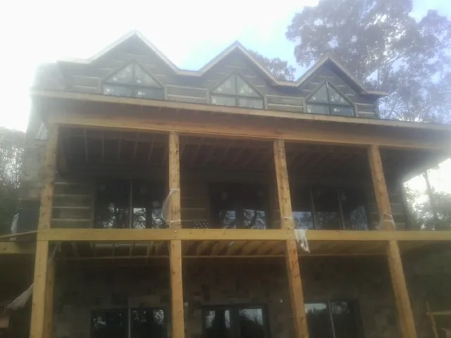Dormers and porch framing on a large log home under construction — Roof Coating work by our crew in Sylvester