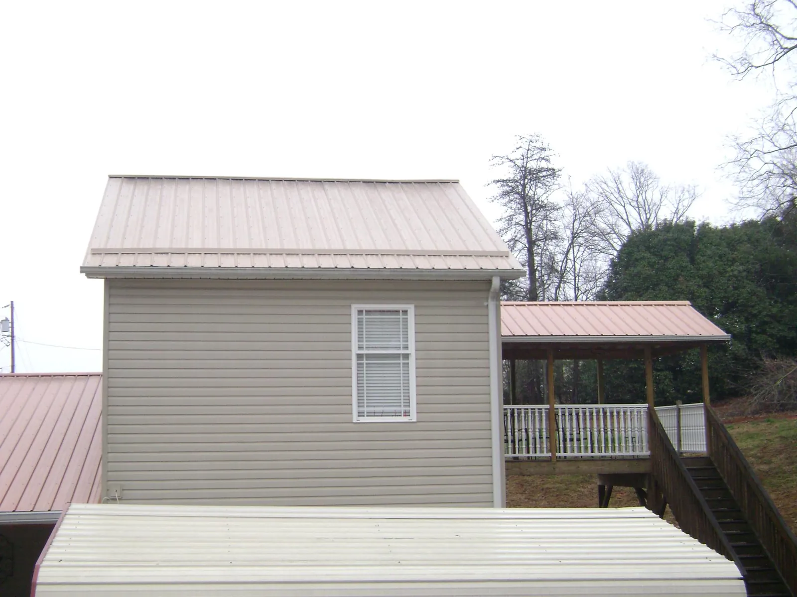 Tan metal roofs on a two story addition and attached porch, from a Roof Replacement job in Sylvester