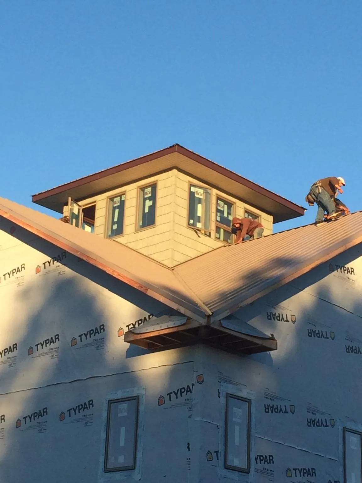 Roofers working around a rooftop cupola on a new metal roof at sunset — Roof Waterproofing in Sylvester by Roofing Brothers